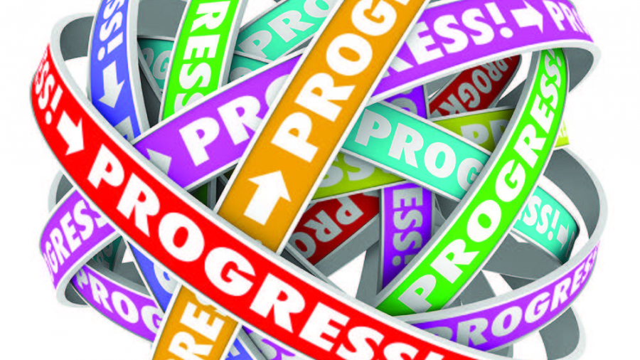 A tangled ball of colorful ribbons, each printed with the word “PROGRESS!” in bold letters and arrows, overlapping and wrapping around each other.