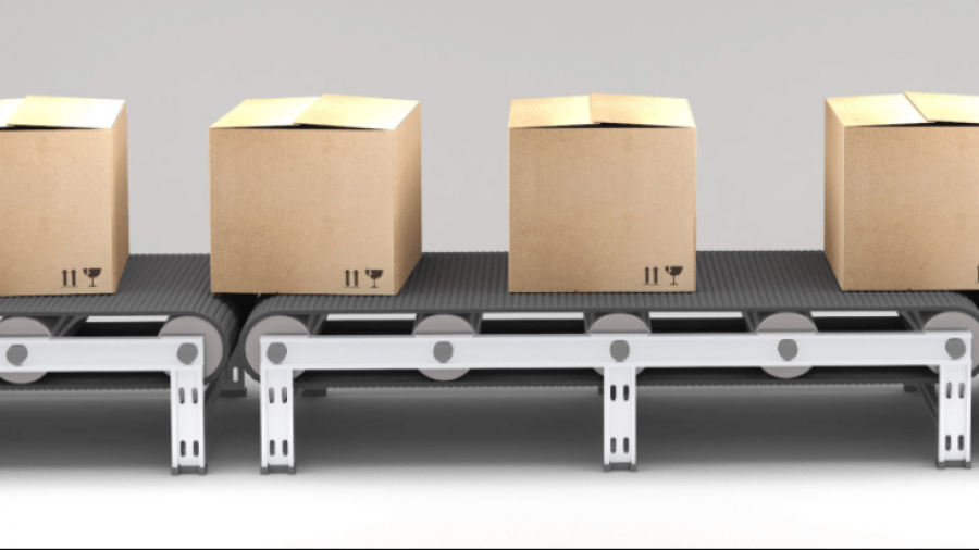 Four closed cardboard boxes are lined up on a conveyor belt, ready for shipping or processing. The background is plain and neutral.