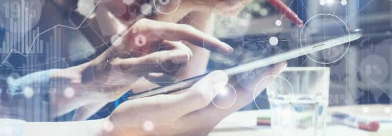 Two people collaborate, using a tablet and stylus at a desk with a glass of water. Overlaid digital graphics suggest technology, data analysis, and innovation.