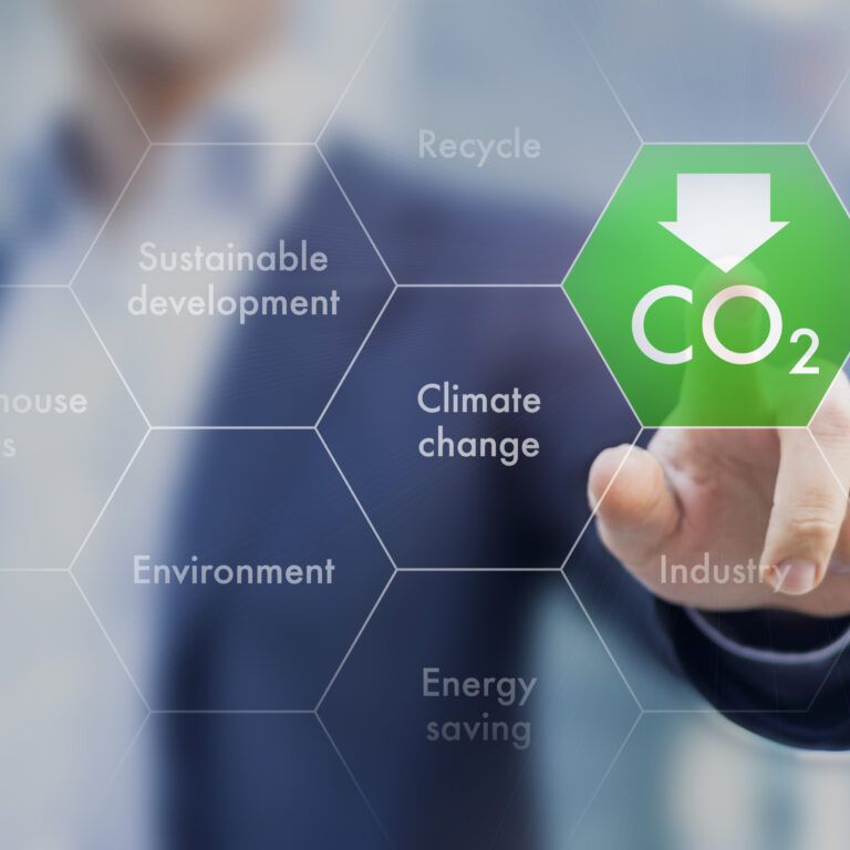 A person in a suit touches a digital hexagon with CO2 and a downward arrow, surrounded by words like climate change, environment, and recycle, symbolizing environmental sustainability.
