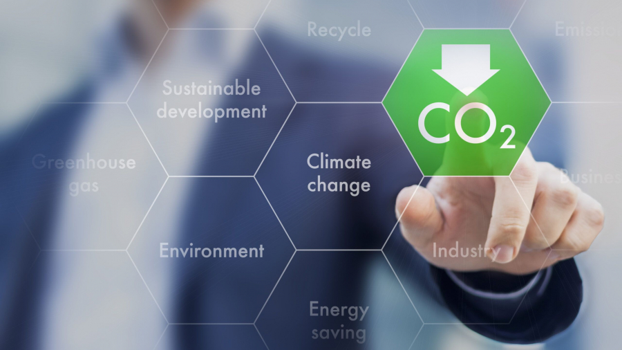 A person in a suit touches a digital hexagon with CO2 and a downward arrow, surrounded by words like climate change, environment, and recycle, symbolizing environmental sustainability.