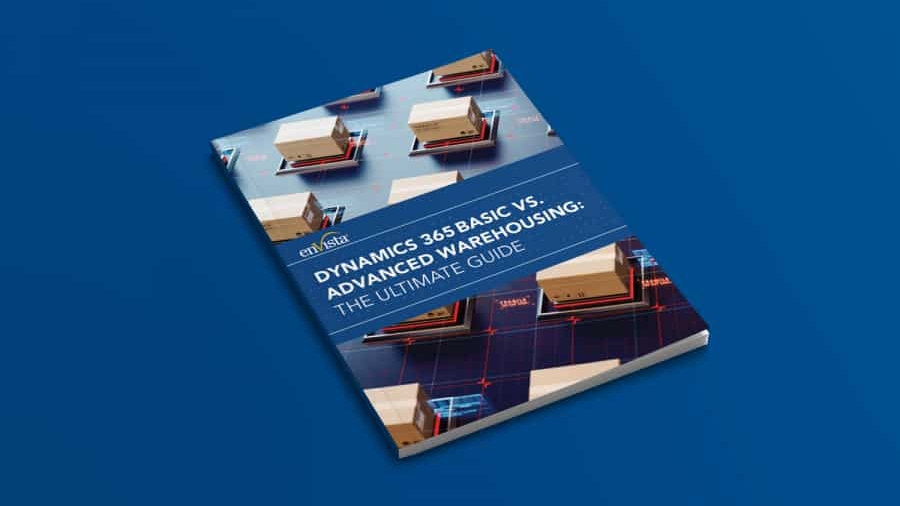 A book titled Dynamics 365 Basic vs. Advanced Warehousing: The Ultimate Guide lies on a blue surface, featuring images of warehouse shelves and boxes on its cover.