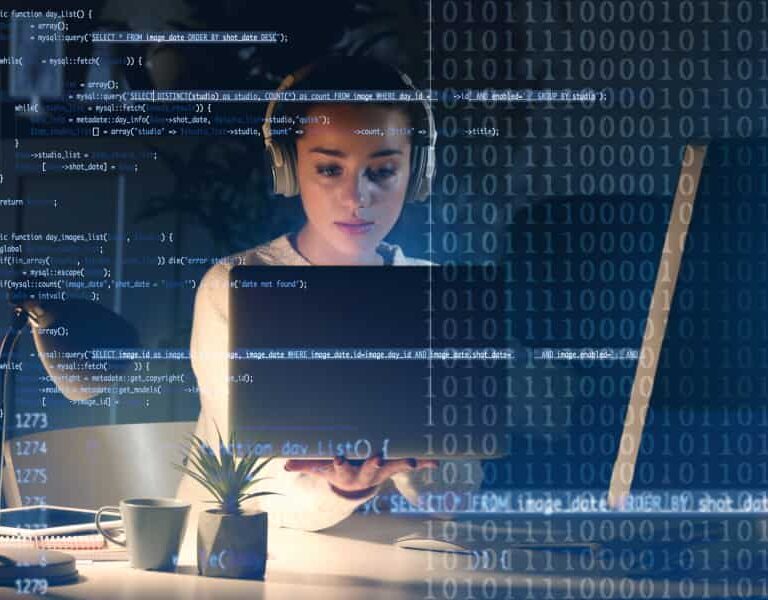 A woman wearing headphones works on a laptop at a desk with a small plant, overlaid with lines of computer code and binary numbers, suggesting programming or cybersecurity work.