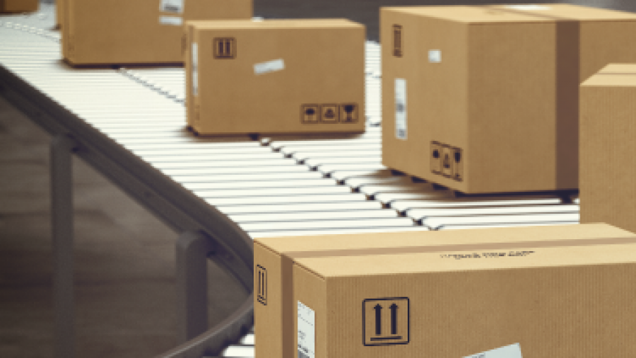 Cardboard boxes with shipping labels move along a conveyor belt in a warehouse or distribution center, illustrating a package sorting or shipping process.