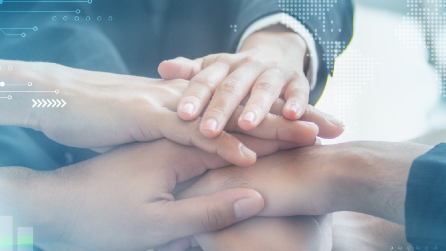 Several people stack their hands together in a gesture of teamwork, with a digital overlay of graphs and a world map, symbolizing global collaboration and business success.