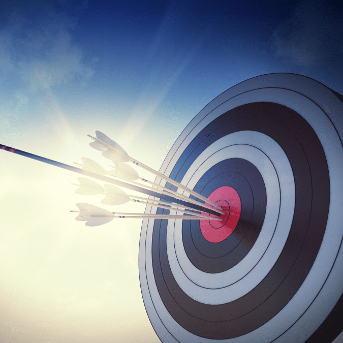 A group of arrows clustered tightly in the bullseye of an archery target, with sunlight and a blue sky in the background, symbolizing precision and accuracy.