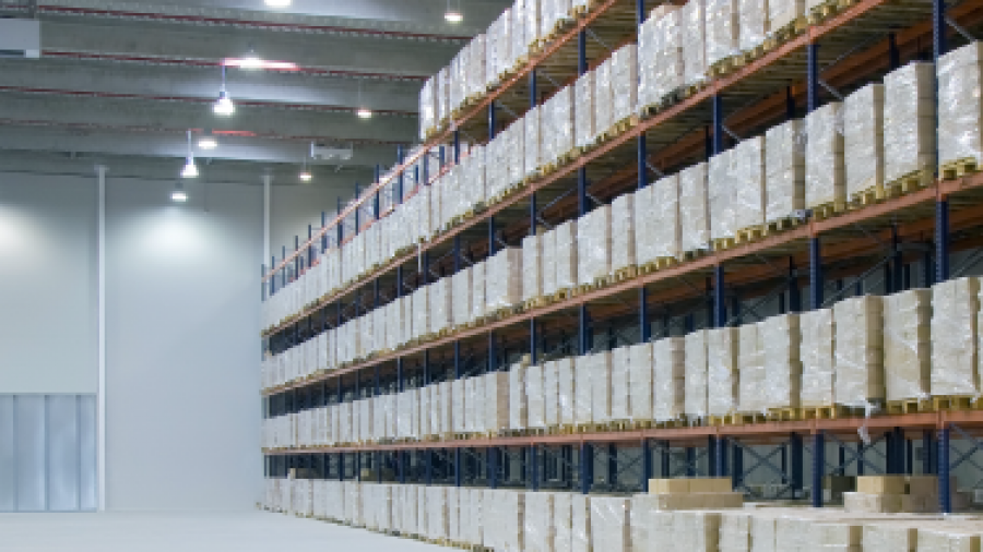 Large warehouse interior with tall racks filled with stacked pallets of goods. The space is brightly lit, featuring warehouse design consulting elements like high ceilings and spacious, clean floors for efficient storage and movement.
