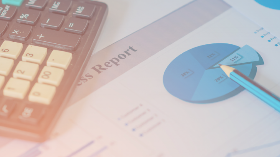A calculator, a blue pencil, and business report papers displaying pie charts and data graphs, suggesting financial analysis or accounting work.