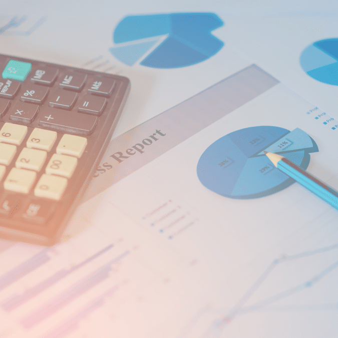 A calculator, a blue pencil, and business report papers displaying pie charts and data graphs, suggesting financial analysis or accounting work.