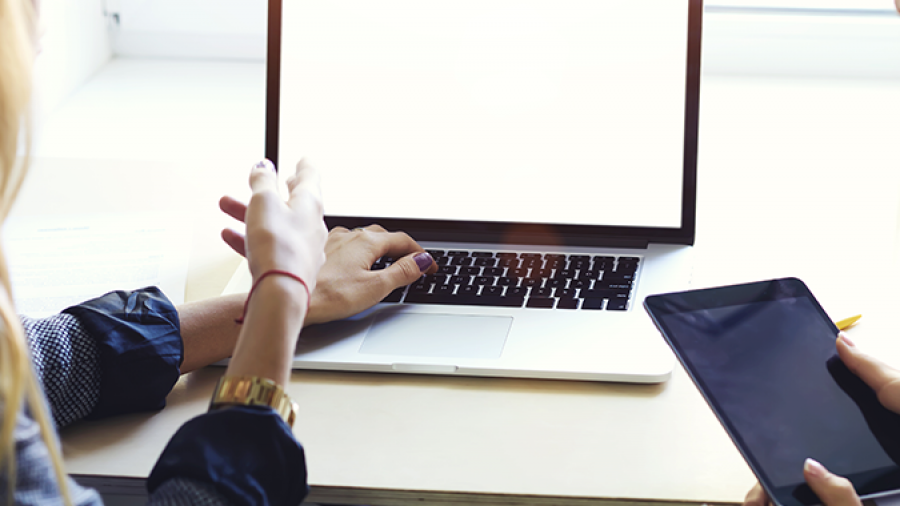 A group of women sitting at a table with a laptop and a tablet.
