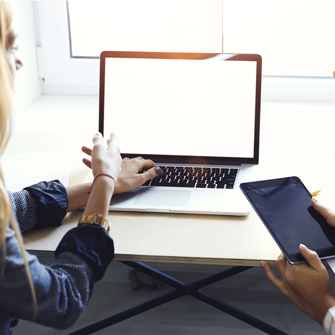 A group of women sitting at a table with a laptop and a tablet.