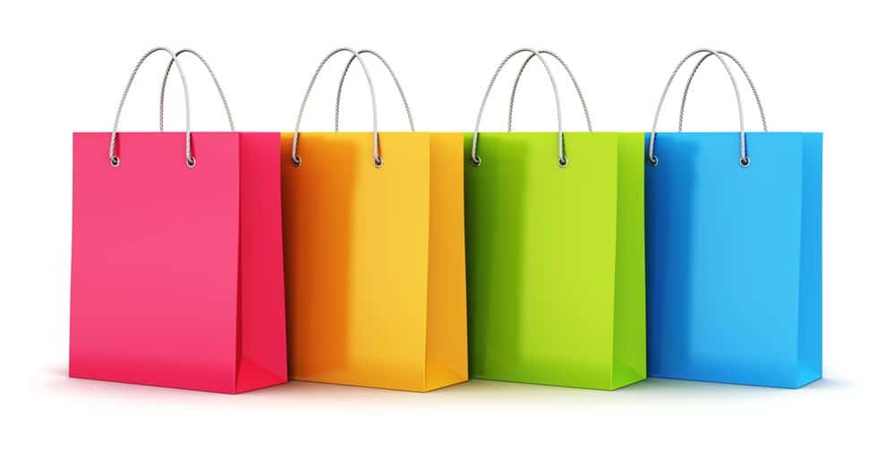 Four shopping bags in bright colors—pink, orange, green, and blue—stand upright in a row against a white background. Each bag has a silver rope handle, showcasing an eye-catching merchandising strategy.