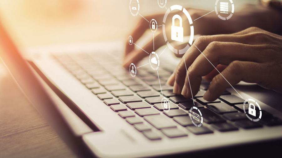 Hands typing on a laptop keyboard with digital security icons and a padlock graphic overlay, representing cybersecurity and data protection.