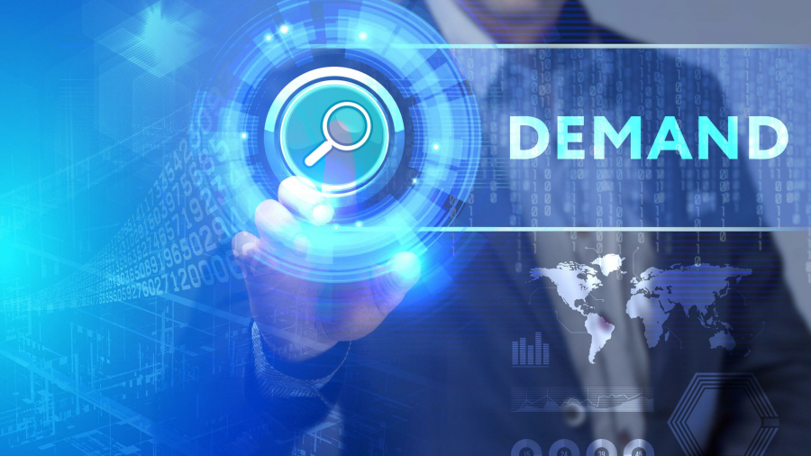 A person in a suit touches a digital search icon on a virtual screen with the word DEMAND displayed, alongside graphics of a world map and abstract data elements.