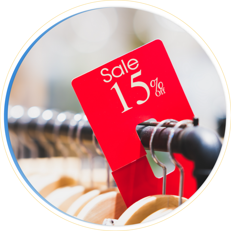 A red sale sign displaying Sale 15% off highlights a pricing promotion, attached to a rack of wooden clothes hangers in a store.