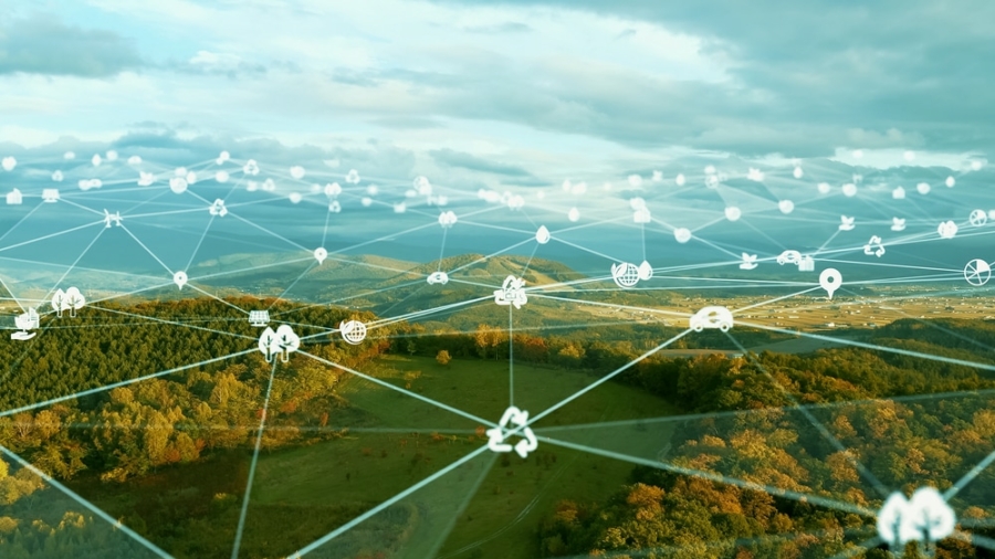 A scenic landscape with hills and forests overlaid by a digital network of interconnected white environmental, technology, and sustainable logistics icons, symbolizing smart environmental monitoring and integrated sustainable technology.