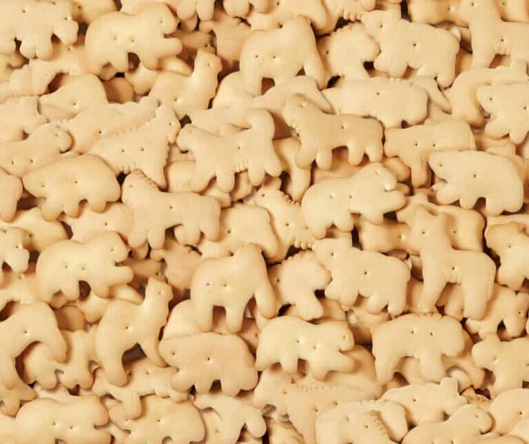 A pile of animal-shaped cookies, including bears, lions, and other animals, closely packed together, creating a textured background.