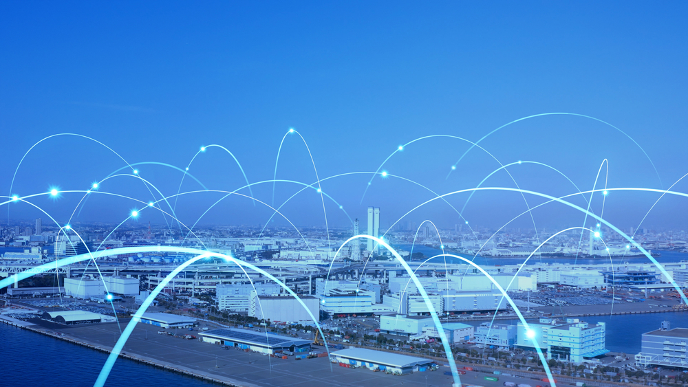 A cityscape by the water with white and blue glowing arcs illustrating a network or data connections, symbolizing connectivity and modern technology in urban infrastructure.