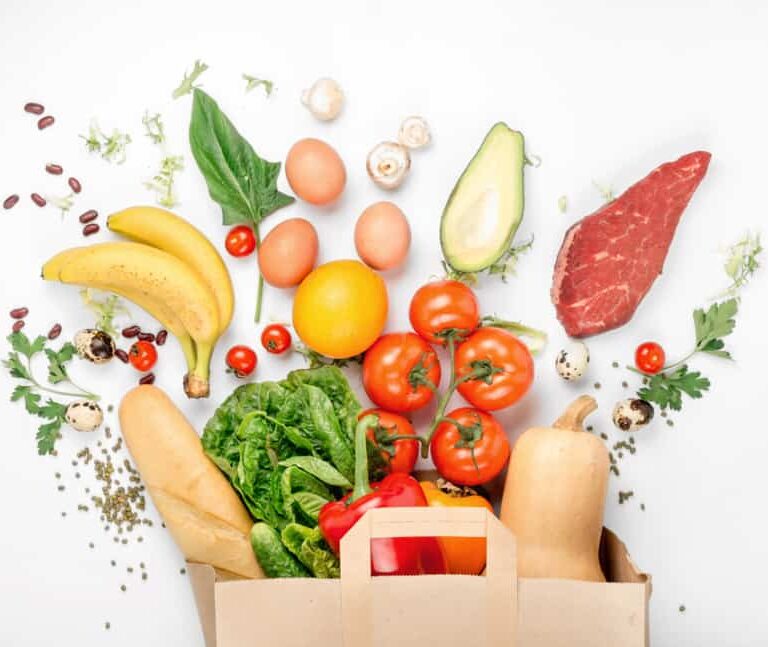 A paper bag overflows with fresh groceries, including tomatoes, lettuce, and more—all carefully selected to highlight supply chain traceability—arranged on a white background.