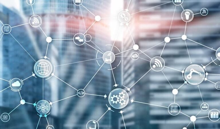 A transparent network of interconnected digital icons, including AMR and gears, overlays a blurred cityscape with modern glass buildings, visually representing what is supply chain strategy in a high-tech urban context.