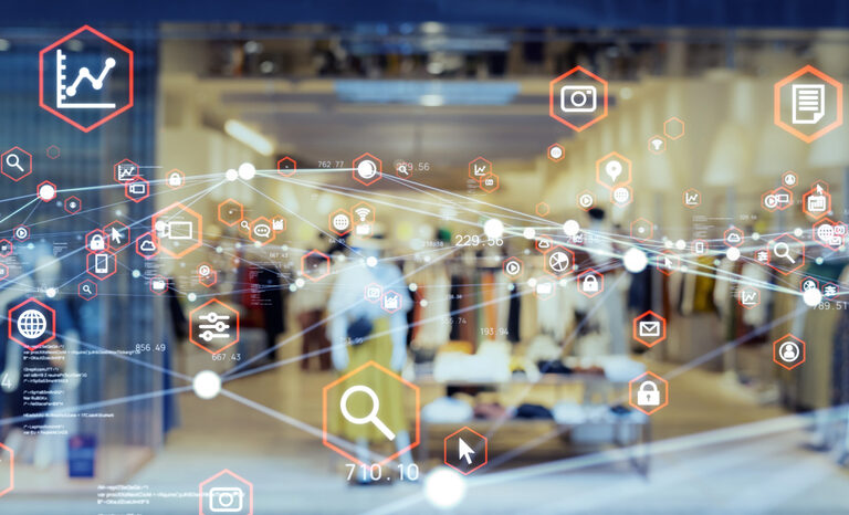 A blurred retail clothing store interior is visible through a glass window overlaid with digital icons representing data, analytics, shopping, and communication, symbolizing how technology shapes modern retail and what supply chain strategy can achieve.
