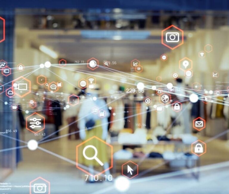 A clothing store interior is seen through a glass wall, overlaid with digital icons symbolizing retail technology and analytics, highlighting the integration of digital information within physical retail spaces.