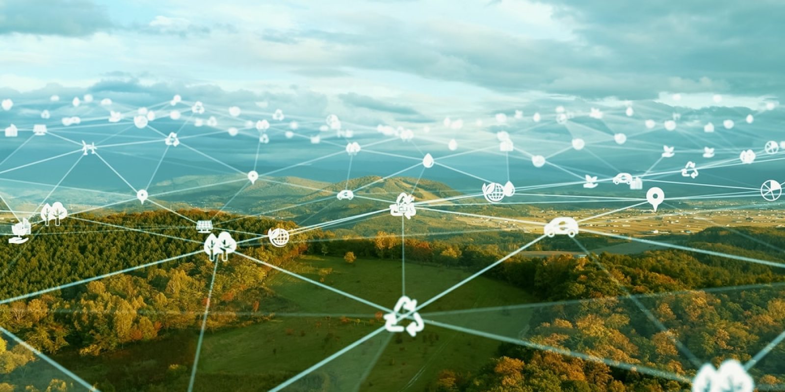 A scenic landscape with hills and forests overlaid by a digital network of interconnected white environmental, technology, and sustainable logistics icons, symbolizing smart environmental monitoring and integrated sustainable technology.