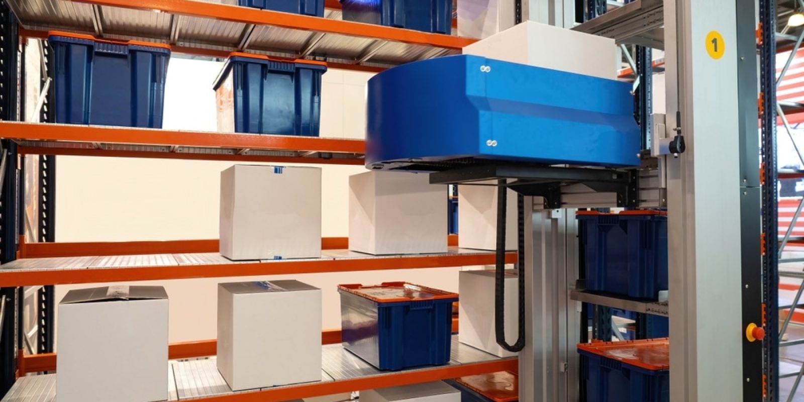 Automated warehouse system with a robotic arm handling white boxes on metal shelves, surrounded by blue storage bins in an organized industrial storage area.