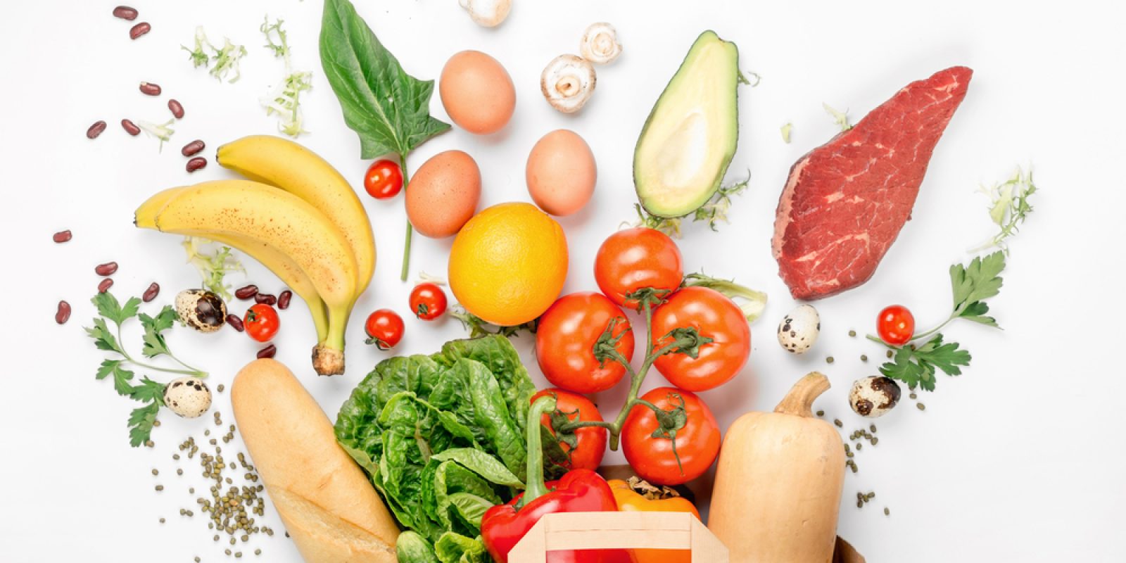 A paper bag overflows with fresh food—tomatoes, lettuce, bananas, bell pepper, baguette, eggs, and more—showcasing the importance of supply chain traceability on a white background.