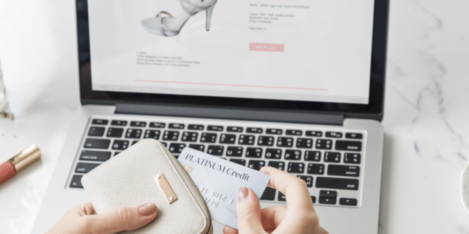 A person holds a beige wallet and a credit card while shopping for shoes online on a laptop. The laptop screen displays a sandal with reviews and a purchase option.