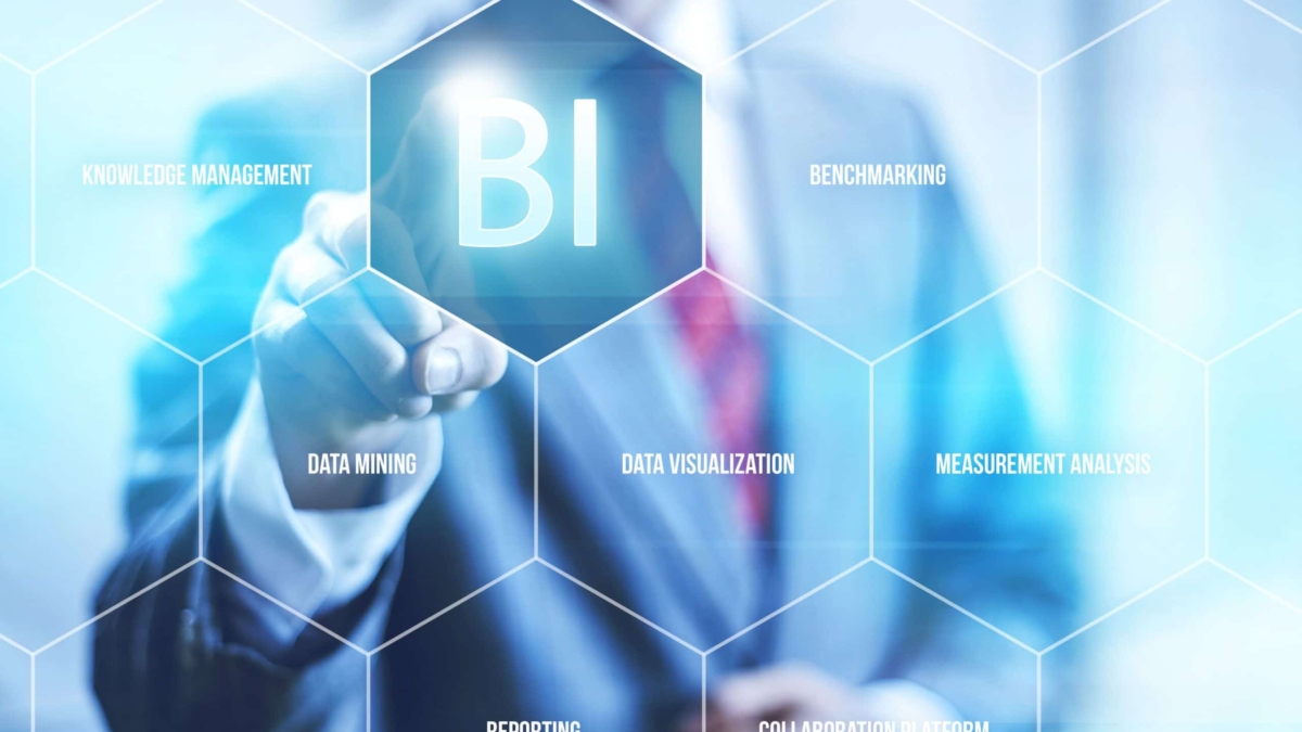 A person in a suit touches a transparent screen displaying hexagons labeled with business intelligence terms like “BI,” “data mining,” “reporting,” and “data visualization.” The background is blurred and professional.