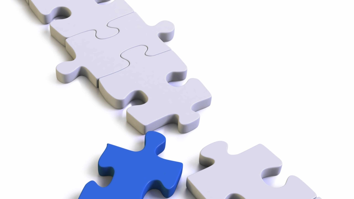 A nearly completed white puzzle with one missing piece, which is blue and placed near the empty spot, ready to be fitted in. The background is white, emphasizing the contrast between the blue and white pieces.