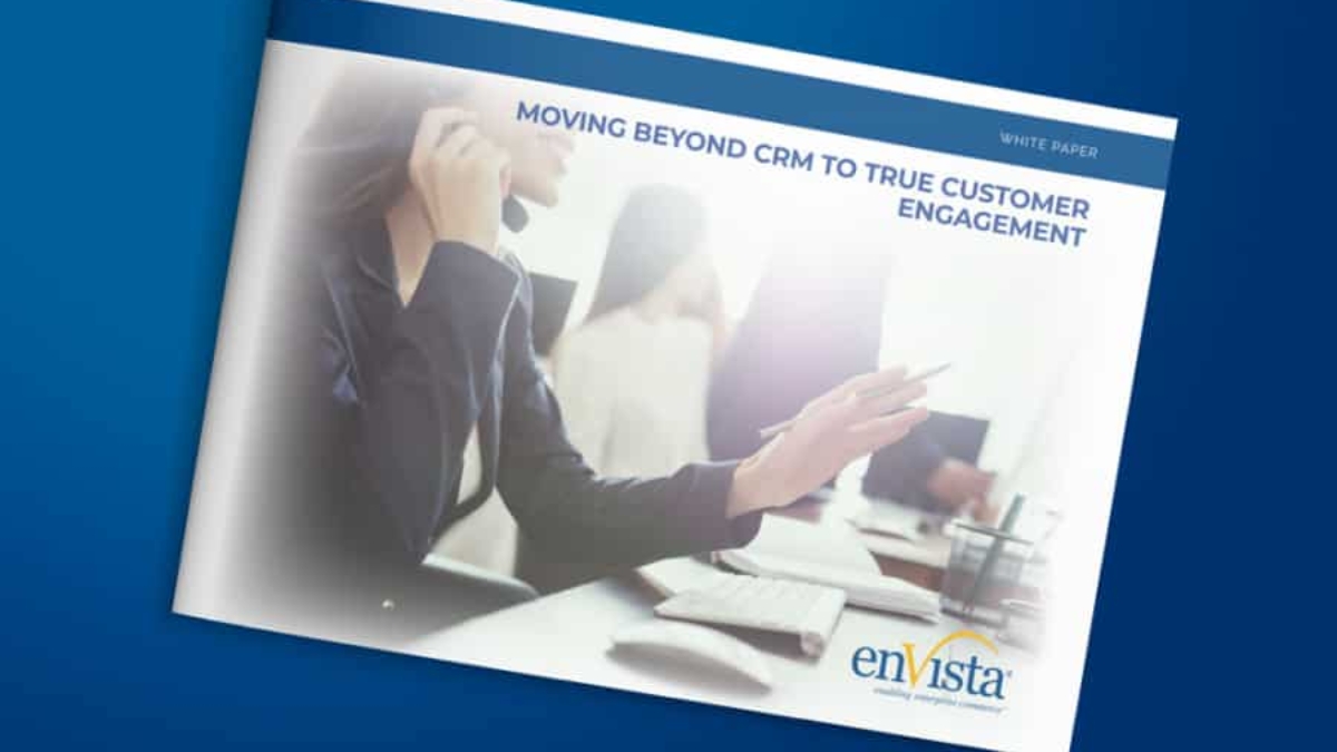 A person wearing a headset sits at a desk with a computer, holding a pen. The cover text reads, Moving Beyond CRM to True Customer Engagement. The enVista logo is at the bottom right corner.