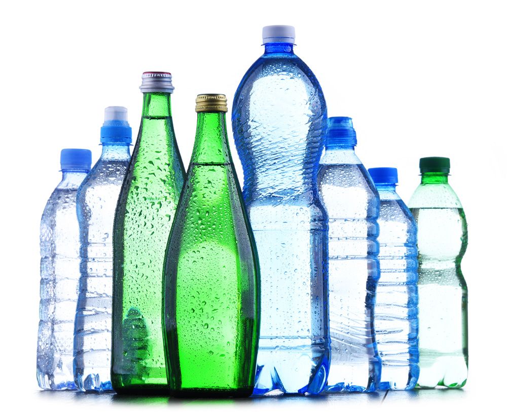 A group of assorted water bottles, both green glass and clear plastic, stand upright on a white background—various shapes and sizes lined up with visible condensation, much like the organized approach found in labor management consulting.
