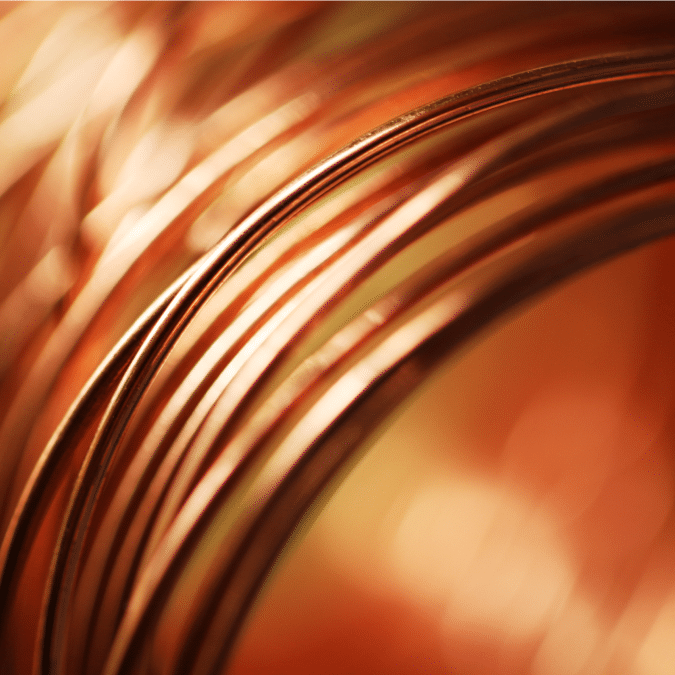Close-up of several loops of copper wire with a warm, orange glow and soft focus in the background.