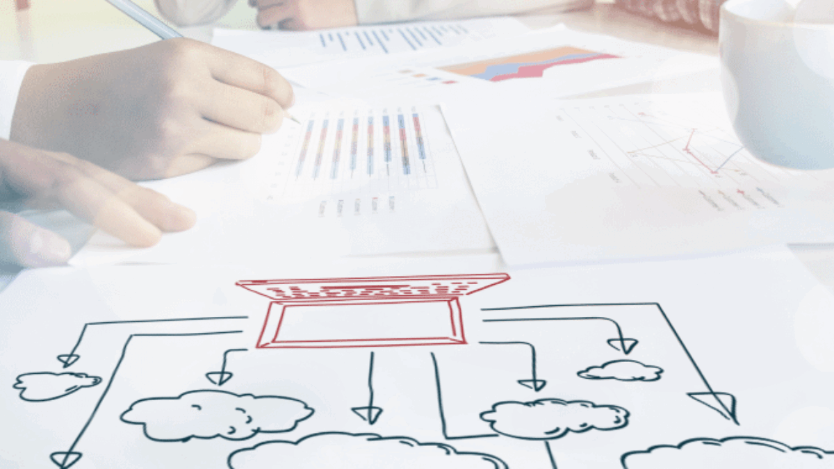 Three people sit at a table reviewing charts and documents. In the foreground, there is a hand-drawn diagram featuring a central box connected by arrows to multiple cloud shapes. A cup is also visible on the table.