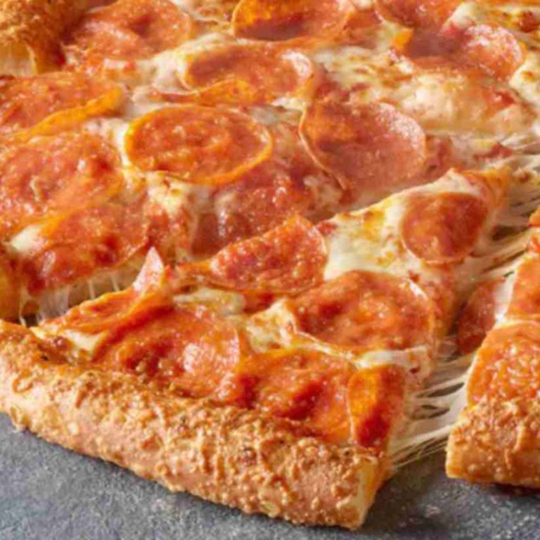 A close-up of a pepperoni pizza with melted cheese and a golden, thick crust. One slice is being pulled away, showing stretchy cheese between the slice and the rest of the pizza.