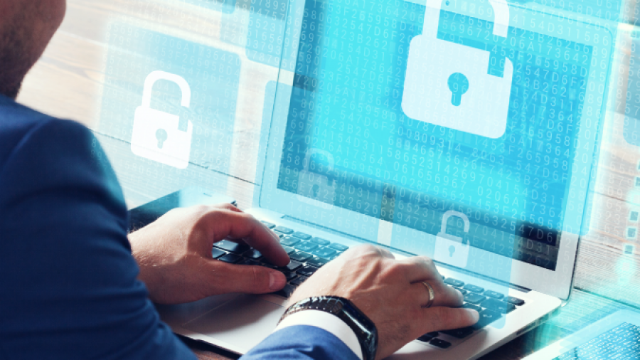 A person in a blue suit uses a laptop displaying digital padlock icons, symbolizing cybersecurity, data protection, and secure IT managed services. Transparent padlock graphics appear around the screen, emphasizing protected access.