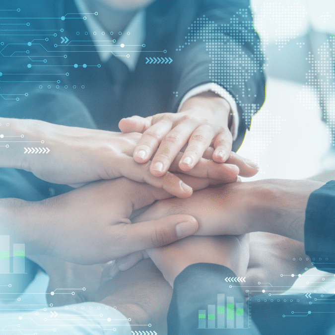 Several people stack their hands together in a gesture of teamwork and unity, with digital graphics of world maps and bar charts overlaying the image, suggesting global business collaboration.