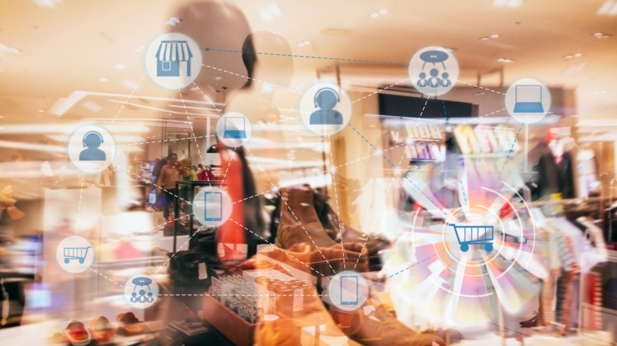 A blurred clothing store interior with digital icons—shopping cart, store, smartphone, and people—connected by lines to represent online shopping, digital retail technology, and enhanced inventory visibility.
