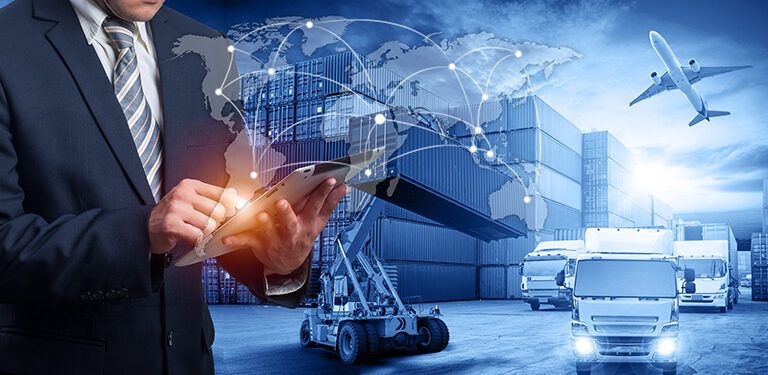 A man in a suit uses a tablet with graphics of a world map and connection lines, overlaid on a background of cargo containers, a forklift, airplanes, and trucks, representing global logistics and supply chain management.