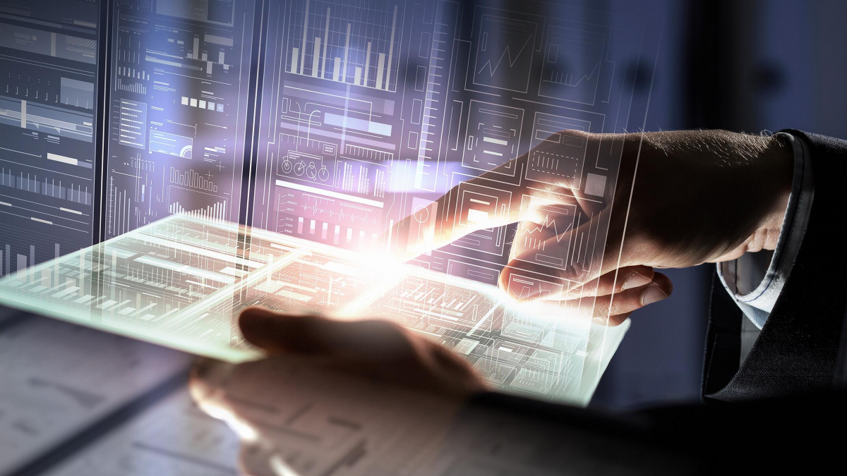 A person’s hand interacts with a glowing transparent tablet, surrounded by futuristic digital data displays and graphs, symbolizing advanced technology and data analysis.