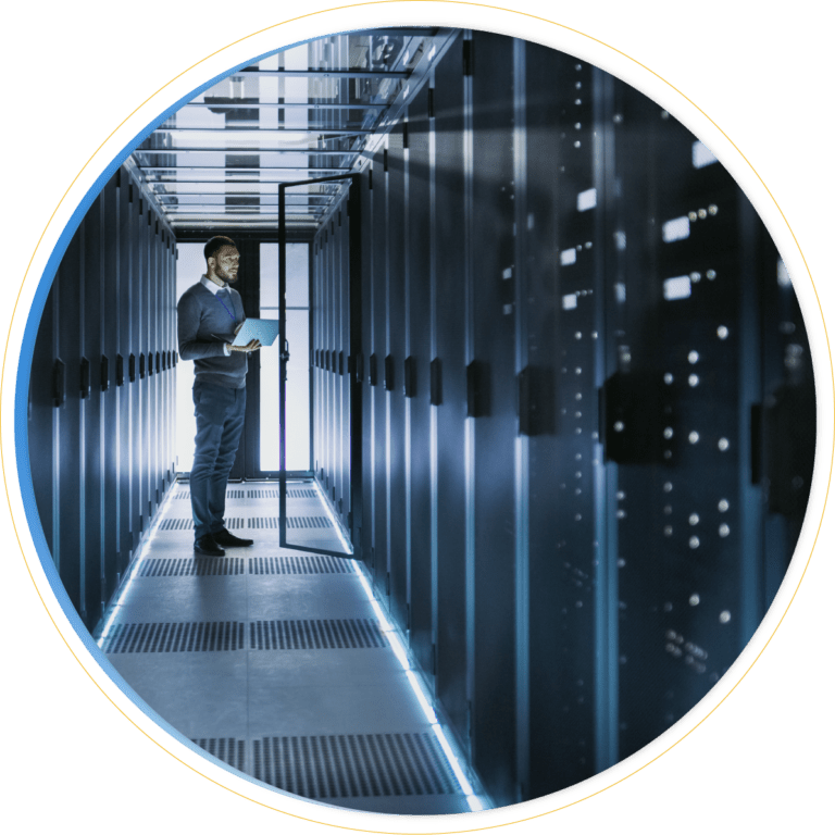 A person stands in a modern, dimly lit server room, holding a laptop and inspecting tall server racks with glowing lights, focused on effective storage management.