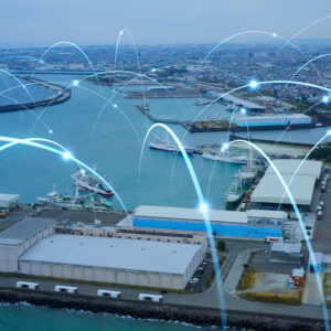 Aerial view of a busy port with warehouses, ships, and blue water. Digital lines and glowing points are overlaid, symbolizing a responsive supply chain with seamless network connectivity and efficient data transfer across the port.
