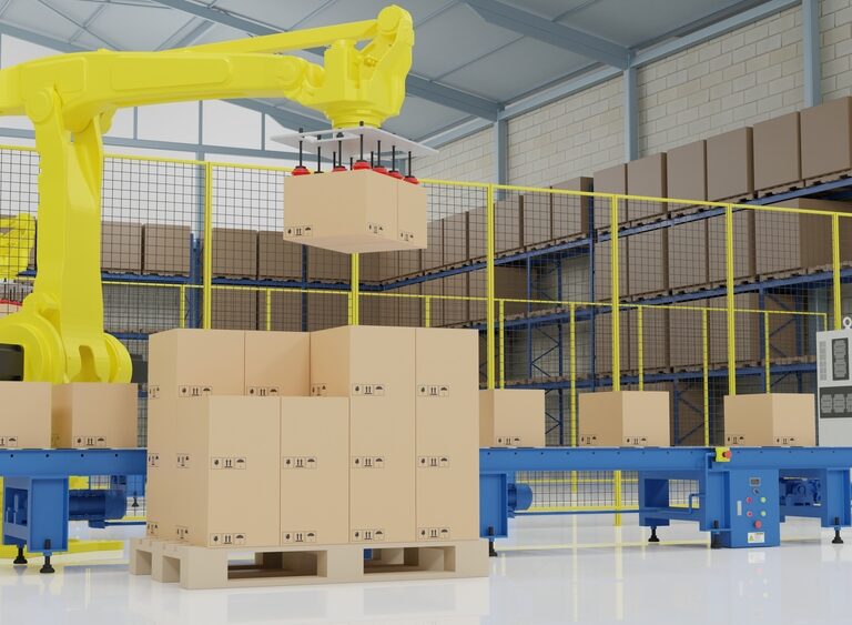 A yellow robotic arm performs automated palletization, moving cardboard boxes onto a conveyor belt in a clean, brightly lit warehouse, with shelves of additional boxes in the background.