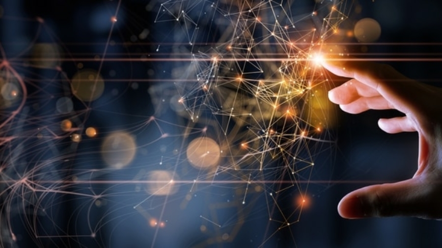 A hand reaches toward glowing, interconnected digital nodes and lines, symbolizing innovation, technology, and networking—echoing what is Microsoft Dynamics 365—against a dark, blurred background with orange light effects.