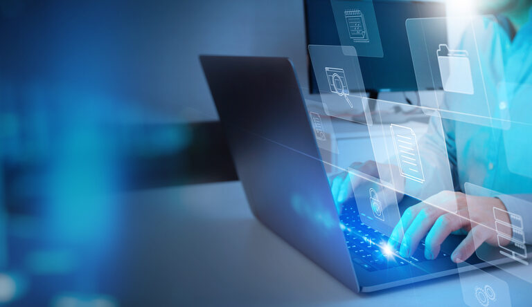 Person typing on a laptop with holographic icons for files, folders, and data storage, symbolizing digital data management and the comparison of business central vs finance and supply chain management in information technology.