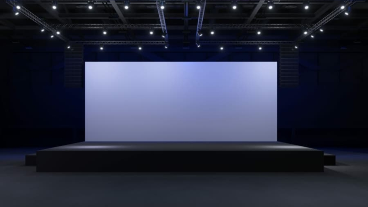 A large, empty stage with a blank screen is illuminated by spotlights in a dark auditorium, setting the scene for a WMS Implementation Case Study presentation or performance.