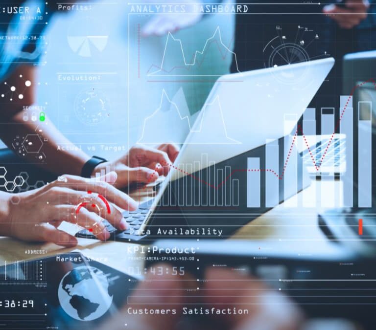 People working on laptops at a desk overlaid with digital graphs, charts, and data analytics visuals, representing teamwork, technology, and business data analysis.