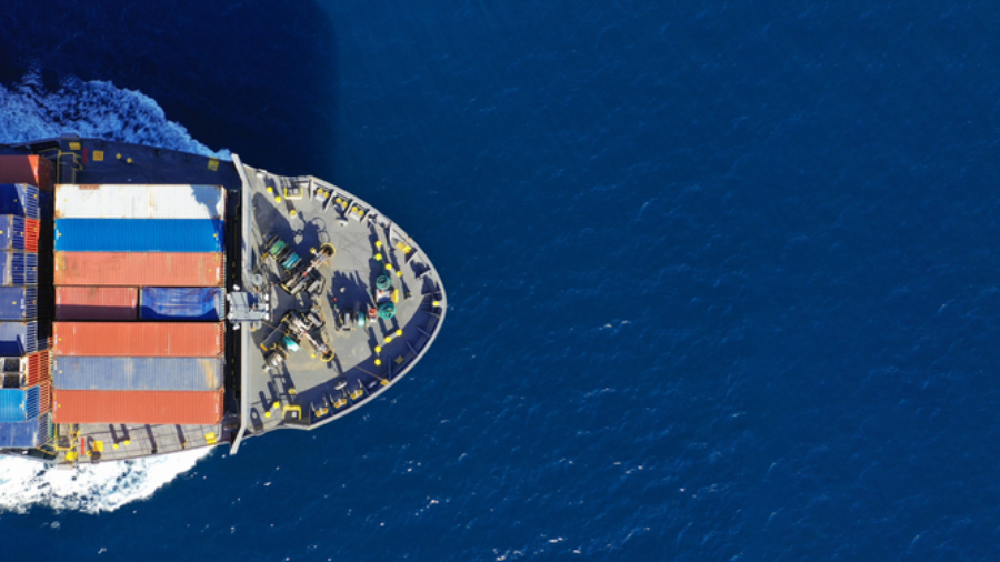Aerial view of a cargo ship carrying colorful shipping containers, sailing through deep blue ocean water—powered by a skilled workforce ensuring smooth global trade.
